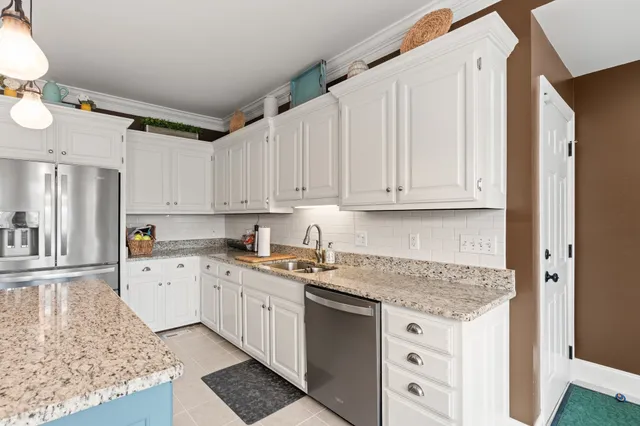 a kitchen with granite countertop a sink stainless steel appliances and white cabinets