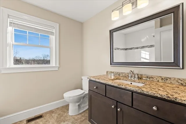 a bathroom with a granite countertop toilet a sink and mirror