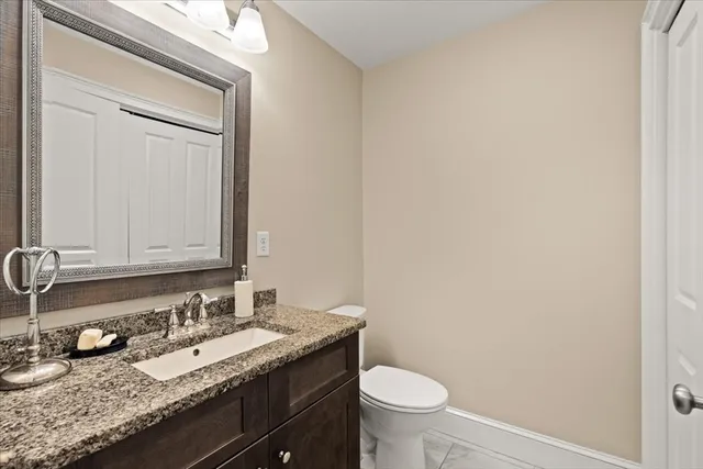 a bathroom with a granite countertop sink and a toilet