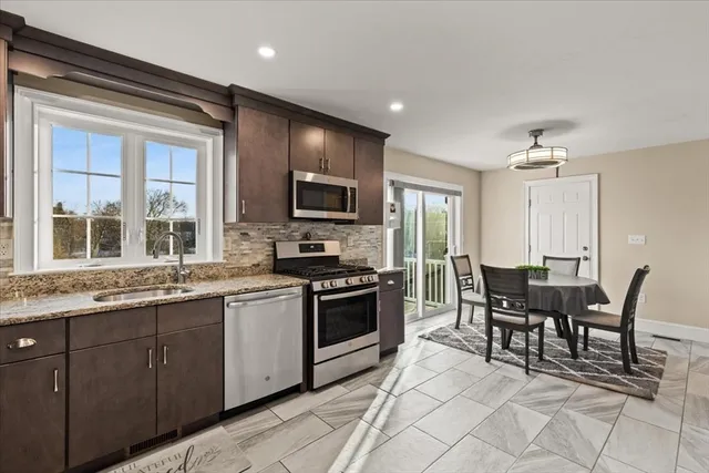 a kitchen with granite countertop cabinets stainless steel appliances a sink and a dining table