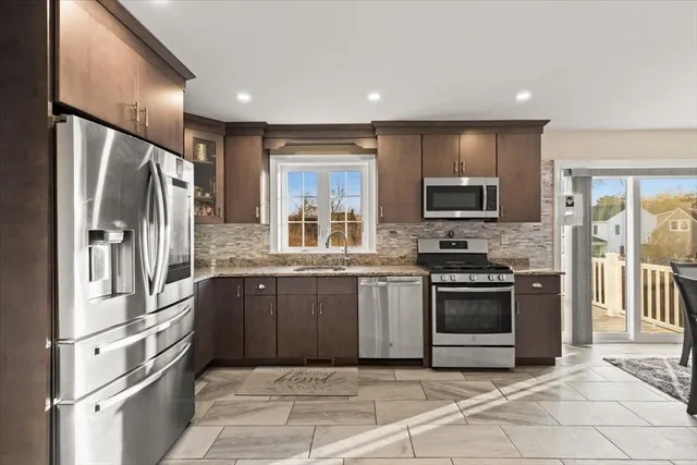a kitchen with stainless steel appliances granite countertop a refrigerator stove top oven and sink
