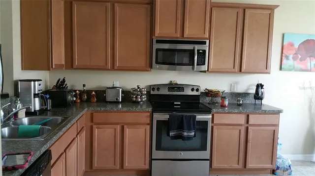 a kitchen with stainless steel appliances granite countertop a stove a sink and a microwave