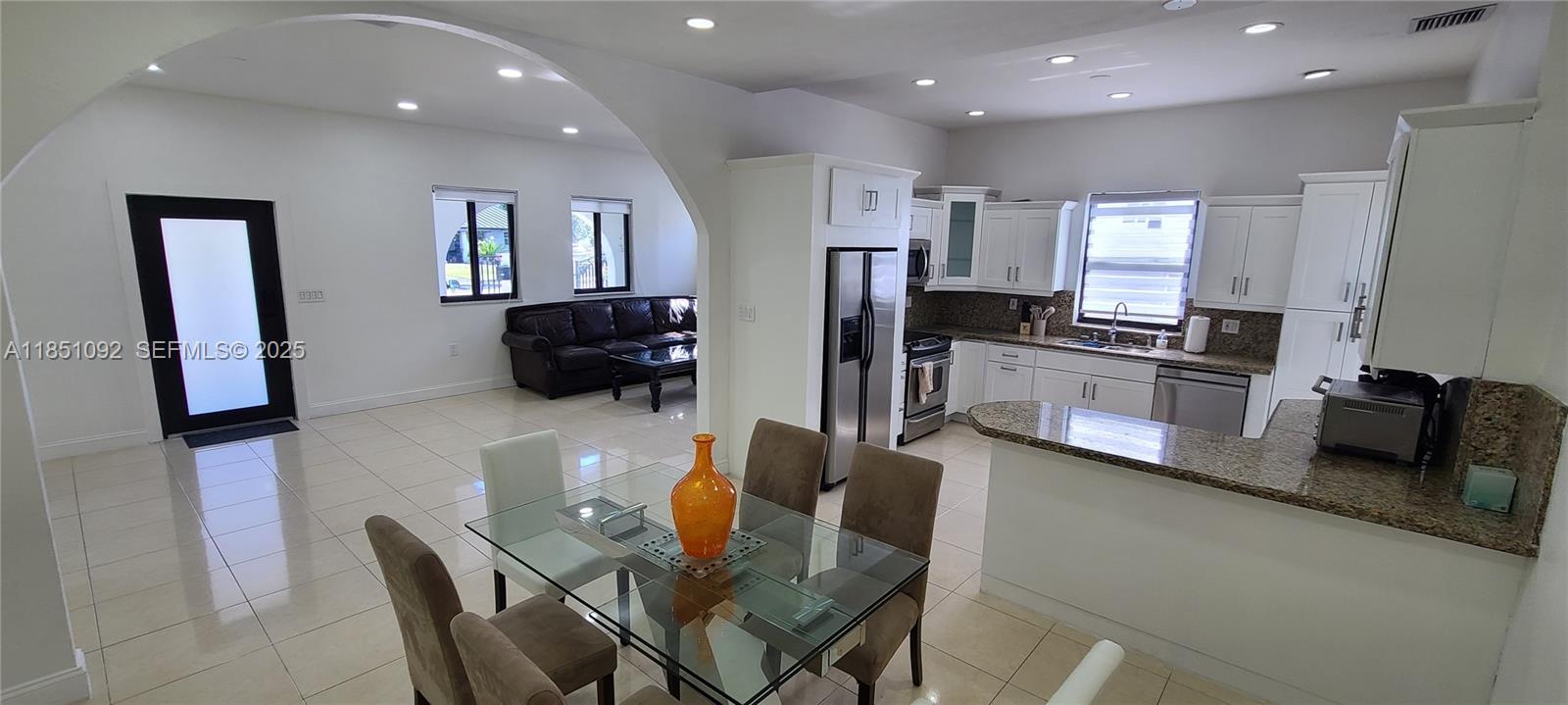 1721 Southwest 24th Terrace Miami, FL 33145 - Photo 4 of 80 a kitchen with stainless steel appliances granite countertop a refrigerator a sink a stove top oven a dining table and chairs with wooden floor