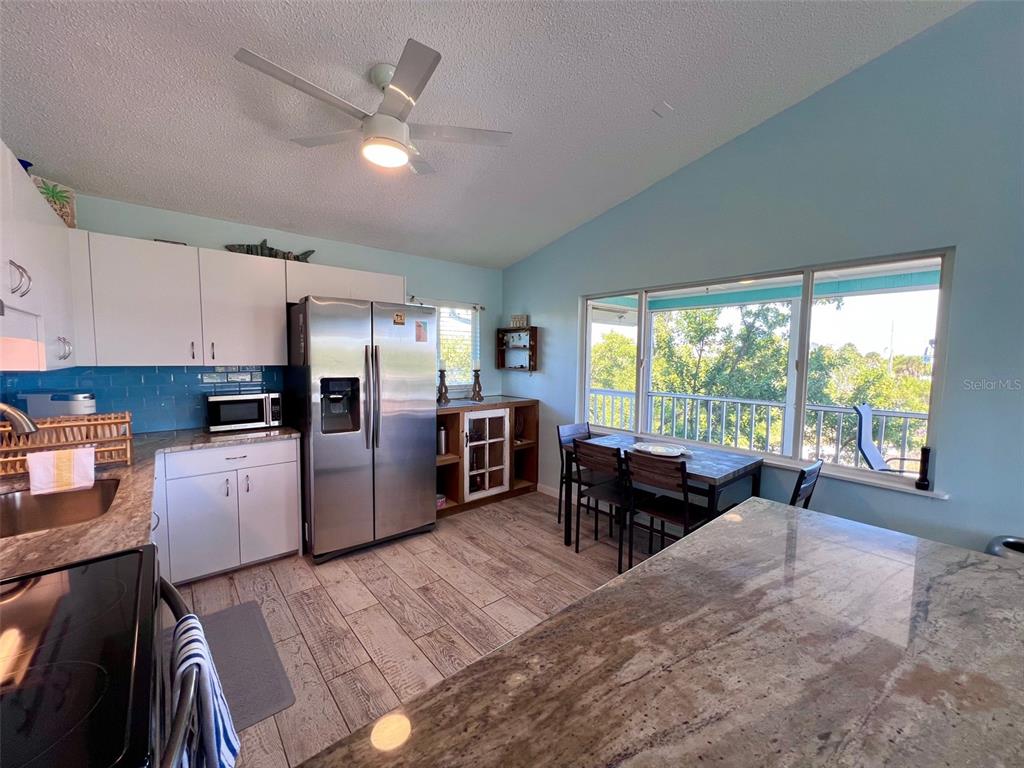 9568 Buccaneer Trail Boca Grande, FL 33921 - Photo 29 of 49 a kitchen with a table chairs refrigerator and cabinets