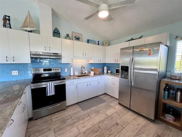 a kitchen with stainless steel appliances granite countertop a refrigerator a stove a dining table and chairs with wooden floor