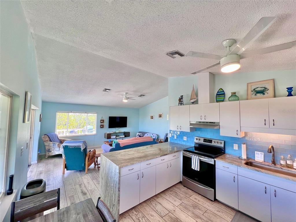 9568 Buccaneer Trail Boca Grande, FL 33921 - Photo 31 of 49 a kitchen with kitchen island granite countertop a stove top oven a sink a dining table and chairs with wooden floor