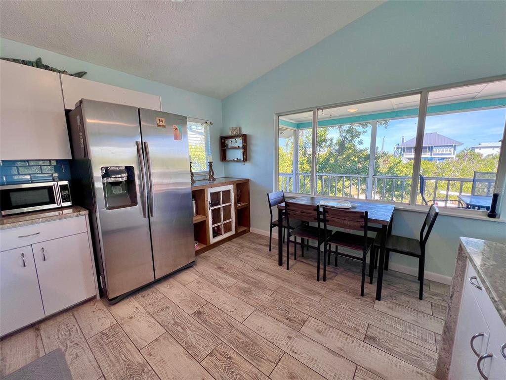 9568 Buccaneer Trail Boca Grande, FL 33921 - Photo 32 of 49 a kitchen with stainless steel appliances granite countertop a refrigerator a stove a dining table and chairs with wooden floor