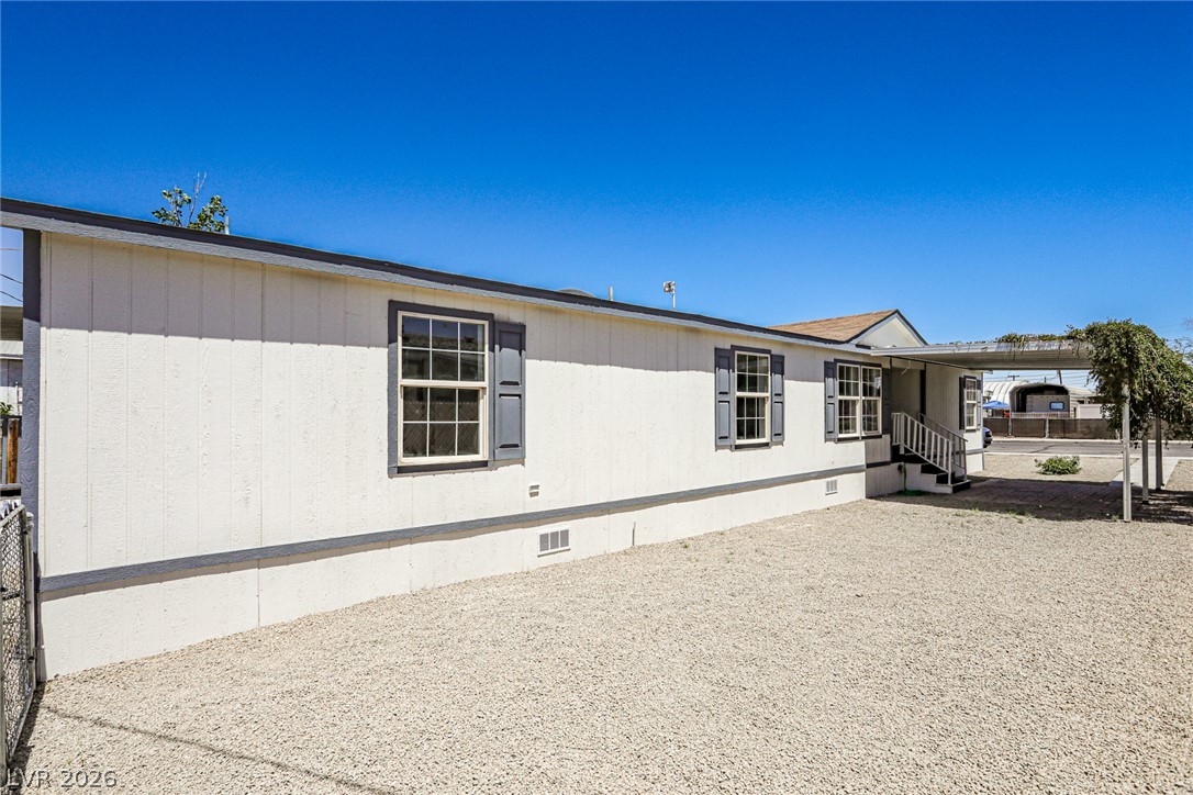 273 Aztec Lane Henderson, NV 89015 - Photo 26 of 28 A well-maintained single-story residence features a gravel lot, covered entrance, and shuttered windows.