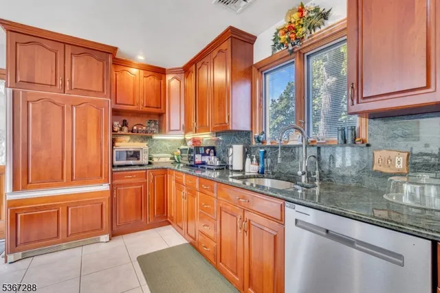 a kitchen with stainless steel appliances granite countertop a refrigerator and wooden cabinets