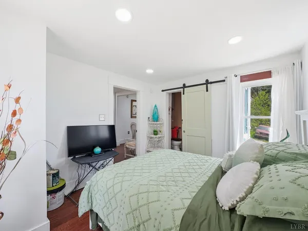 a bedroom with a bed a computer on desk and a window