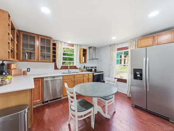 a kitchen with granite countertop a refrigerator a stove a sink dishwasher a dining table and chairs with wooden floor