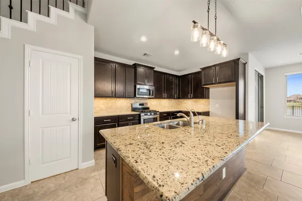 a kitchen with stainless steel appliances granite countertop a sink a stove and a refrigerator