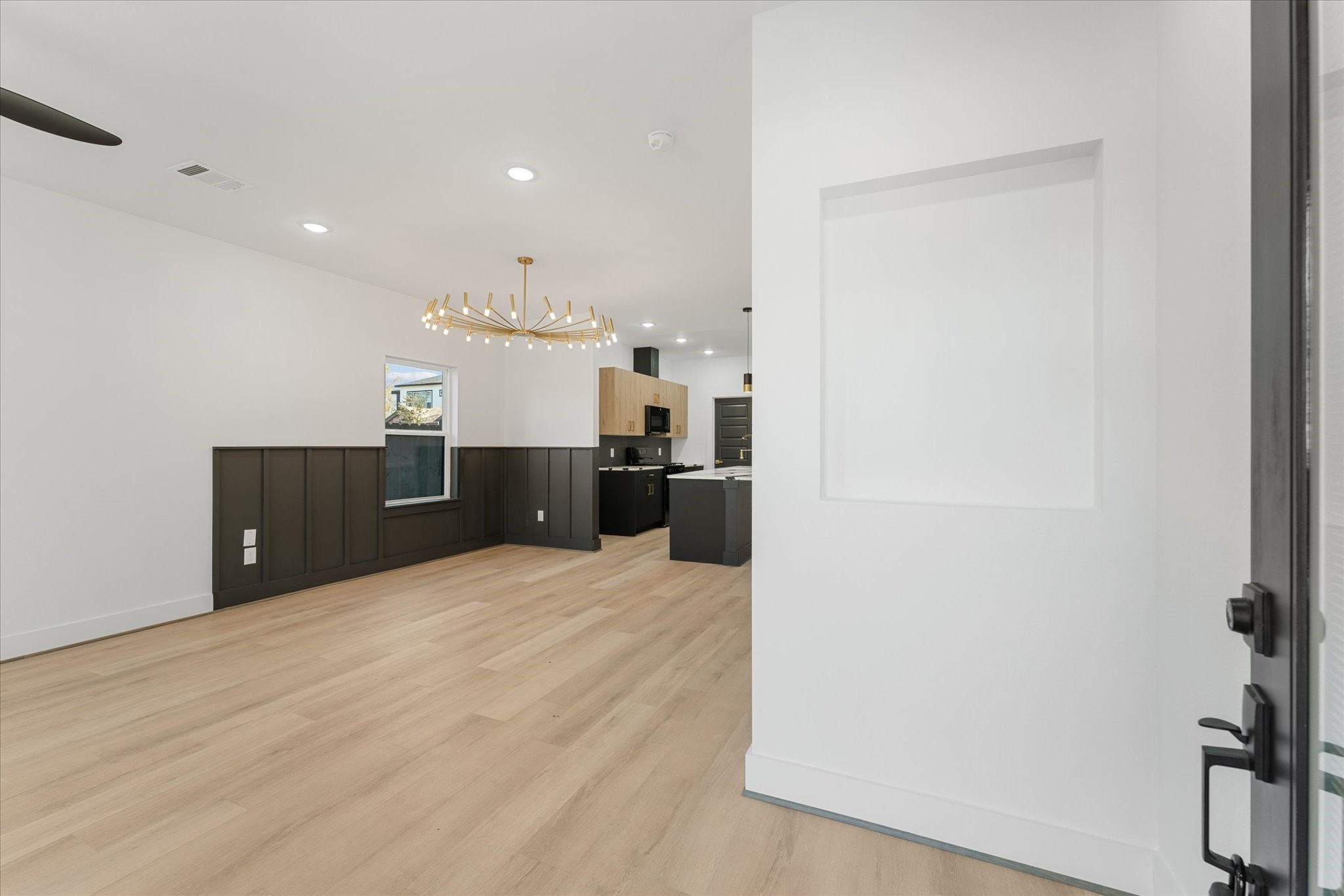 1010 Calvin Street Houston, TX 77088 - Photo 6 of 20 Modern, open concept living space with light flooring. It features a sleek chandelier, contemporary cabinetry, and ample natural light, leading into a stylish kitchen area. Photos are from builders previously built model with same floor plan and finishes.