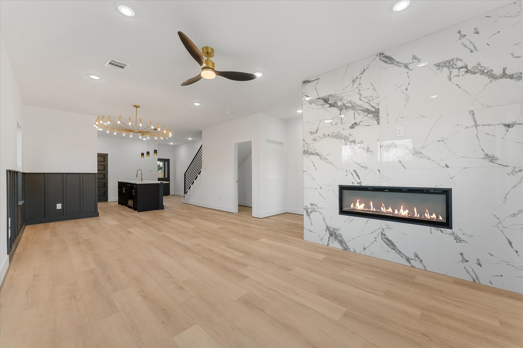 1010 Calvin Street Houston, TX 77088 - Photo 7 of 20 Living space features an open floor plan with, a striking tile accent wall with a sleek fire place. The room flows seamlessly into a kitchen area with a contemporary chandelier and a central island, perfect for entertaining. Photos are from builders previously built model with same floor plan and finishes.