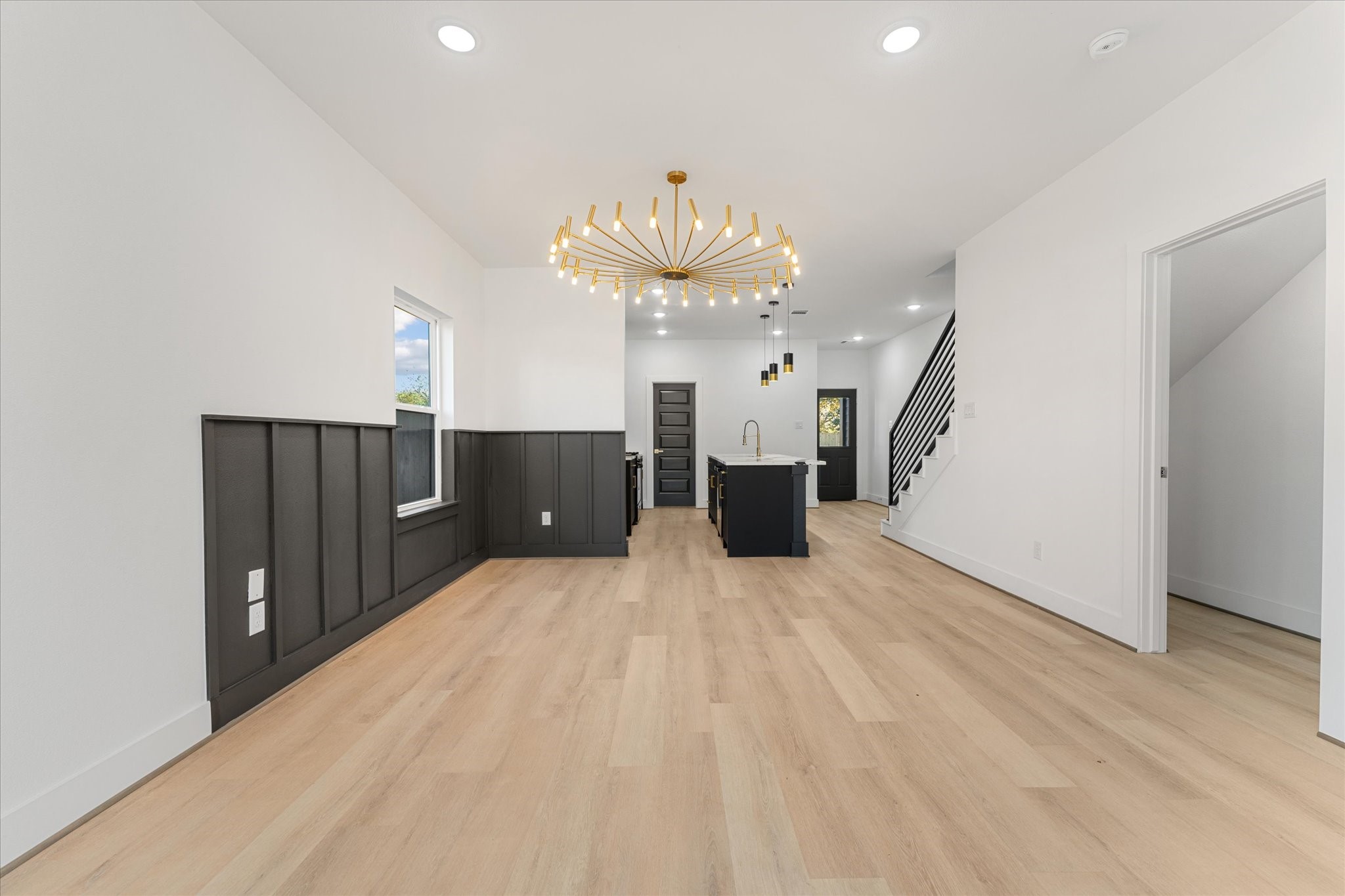 1010 Calvin Street Houston, TX 77088 - Photo 8 of 20 Open concept living space features light flooring, sleek black wainscoting, and a striking chandelier. The kitchen at the back boasts a central island and contemporary fixtures. Photos are from builders previously built model, same floor plan and finishes.