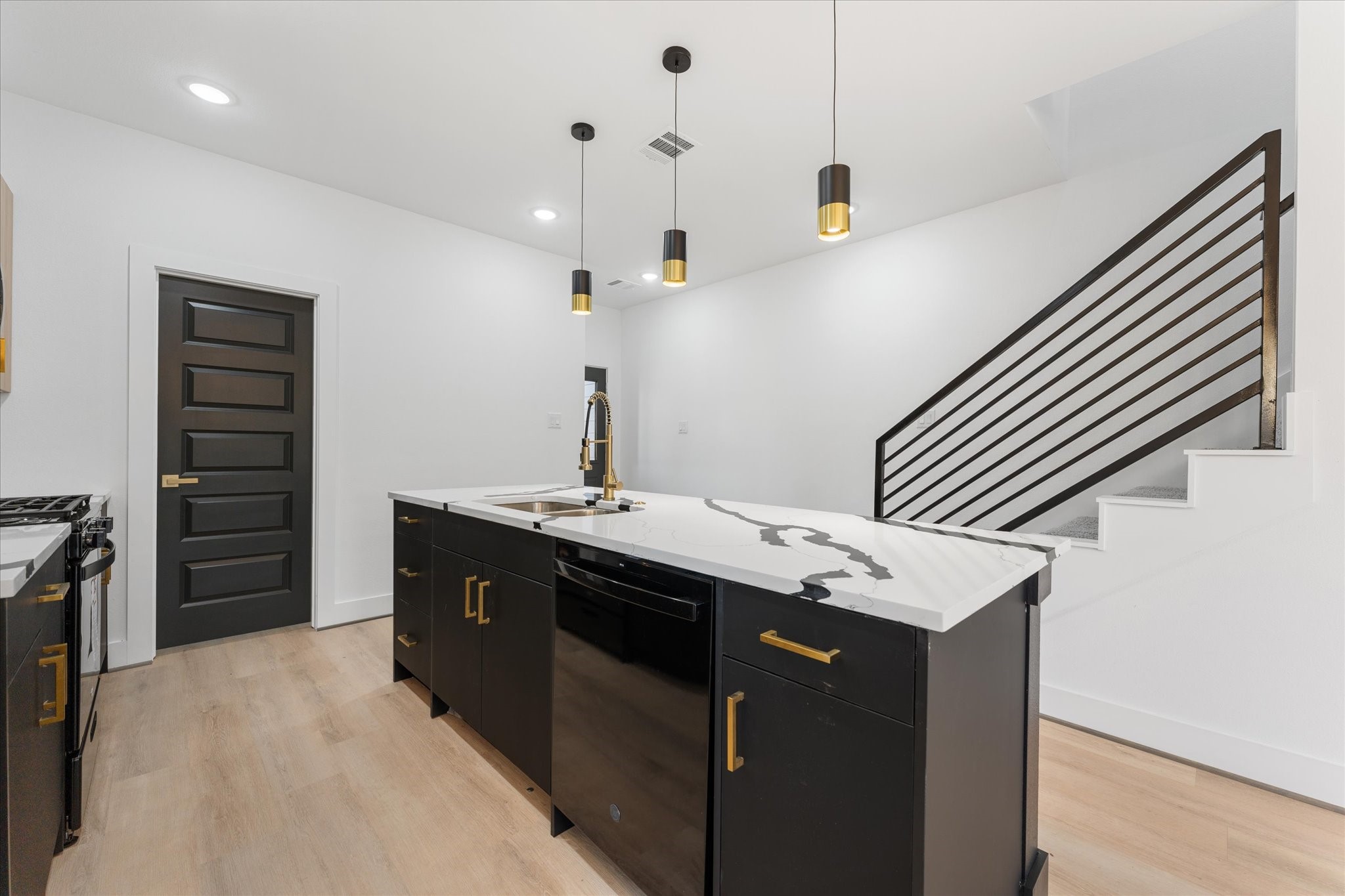 1010 Calvin Street Houston, TX 77088 - Photo 10 of 20 This modern kitchen features sleek black cabinetry with gold hardware, a striking countertop island, and pendant lighting. Photos are from builders previously built model, same floor plan and finishes.