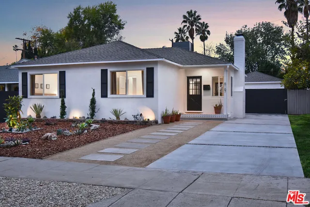 a front view of a house with a yard and potted plants