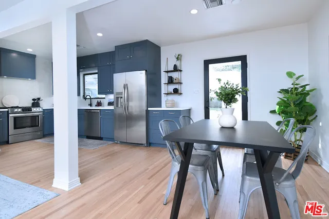 a kitchen with stainless steel appliances a dining table chairs and refrigerator
