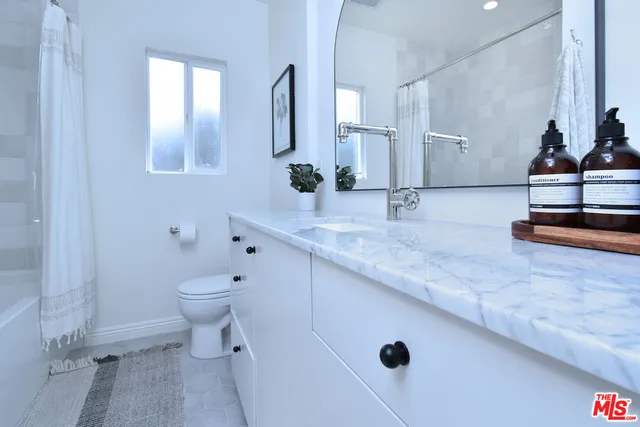 a bathroom with a granite countertop sink a toilet and a mirror