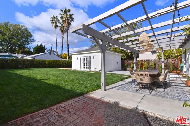 a view of a patio with table and chairs potted plants and a big yard