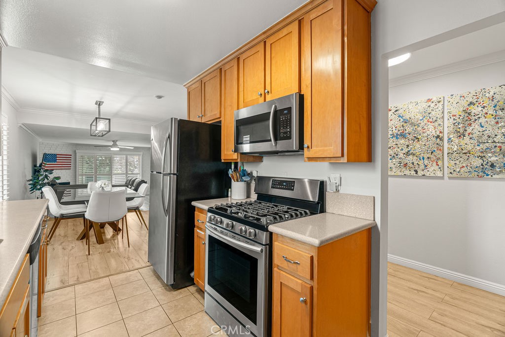 1321 Beryl Street, Unit 101 Redondo Beach, CA 90277 - Photo 9 of 40 a kitchen with stainless steel appliances granite countertop a stove top oven a sink dishwasher a refrigerator and a dining table with wooden floor