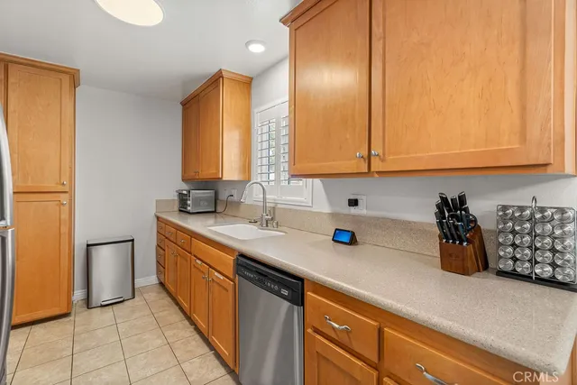 a kitchen with stainless steel appliances a sink dishwasher refrigerator and cabinets