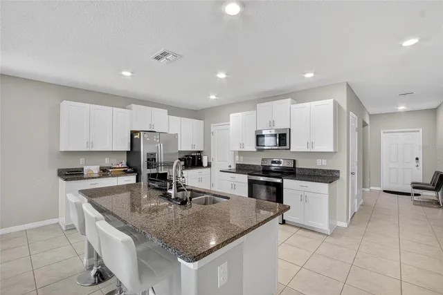 a kitchen with granite countertop a stove sink and refrigerator