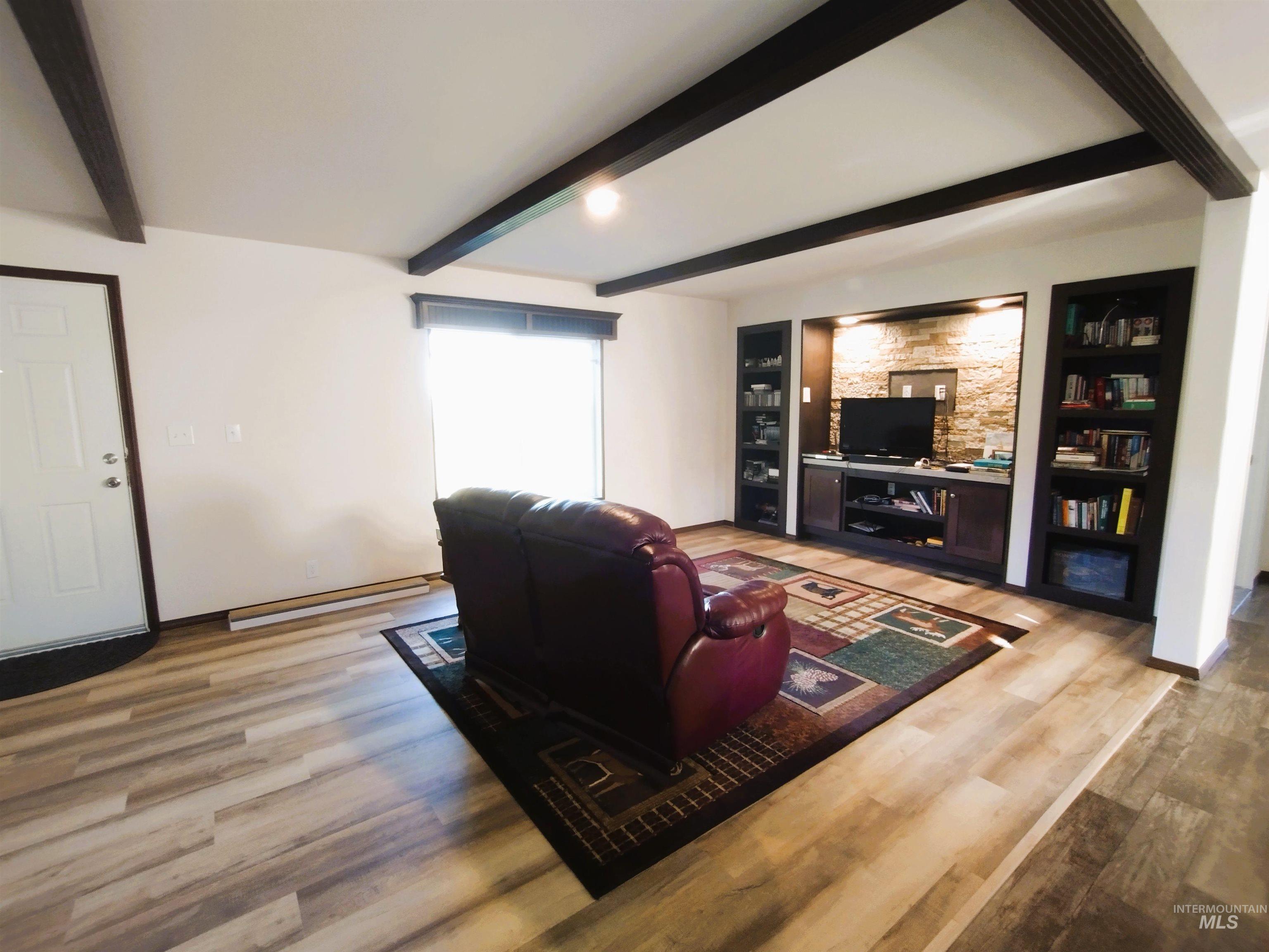 142 Shenandoah Third Street Kamiah, ID 83536 - Photo 23 of 50 Living room featuring light wood-style flooring, built in shelves, beam ceiling, and a baseboard radiator