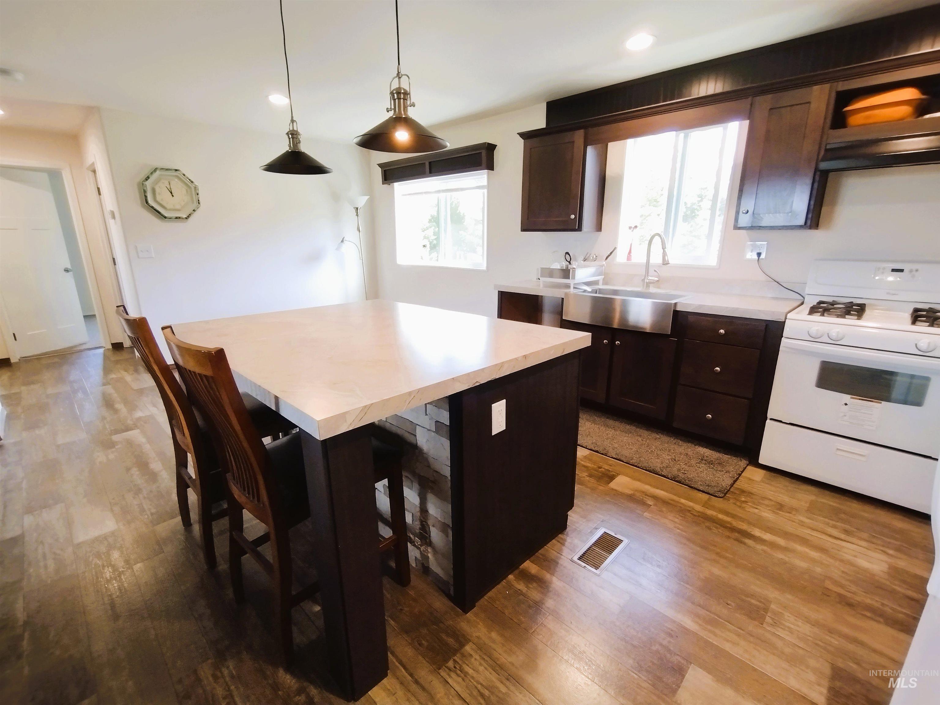 142 Shenandoah Third Street Kamiah, ID 83536 - Photo 25 of 50 Kitchen featuring white gas range, dark wood finish cabinetry, a kitchen breakfast bar, and light wood finished floors
