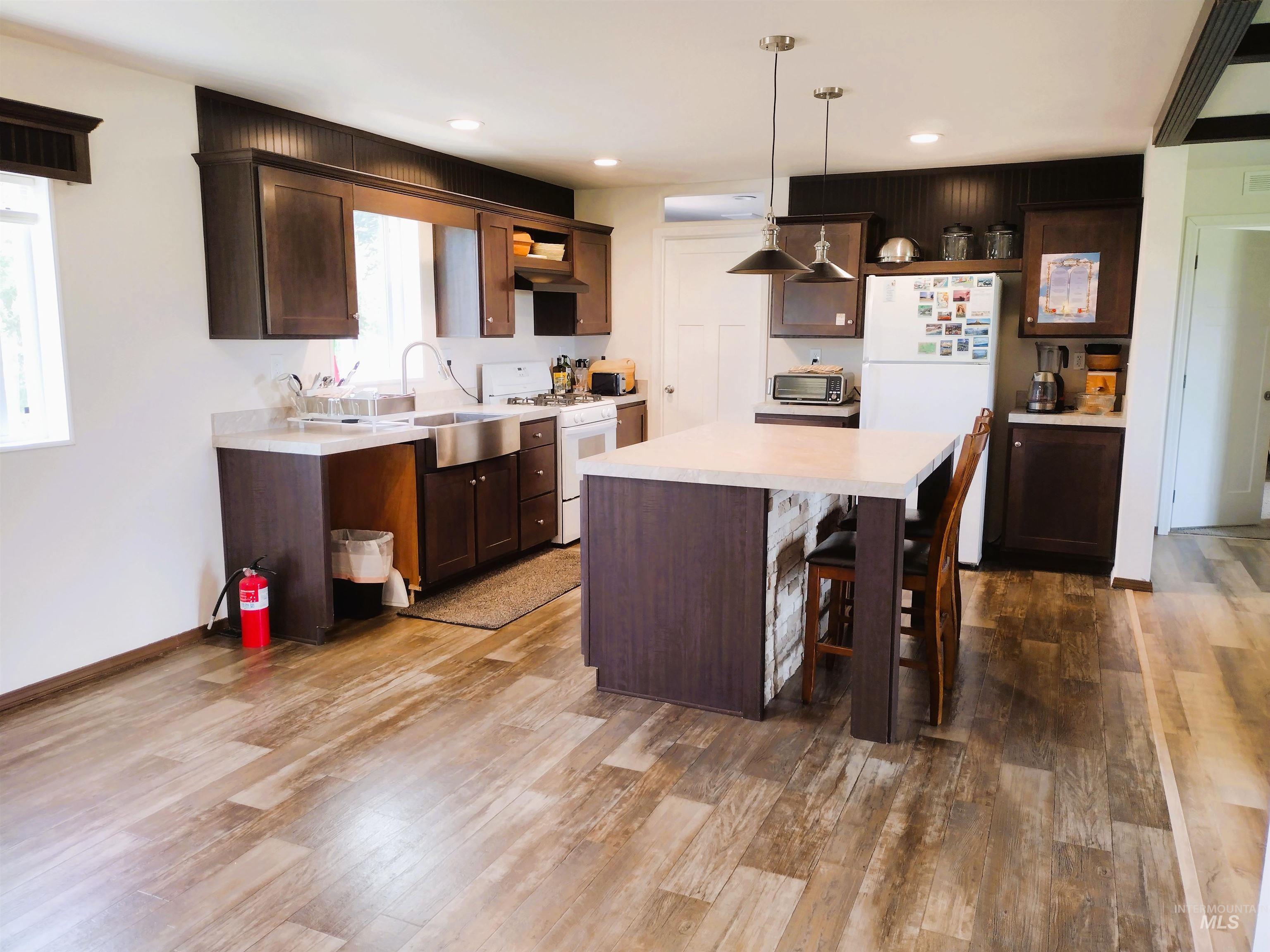 142 Shenandoah Third Street Kamiah, ID 83536 - Photo 27 of 50 Kitchen featuring light countertops, white appliances, dark wood finish cabinetry, and a center island