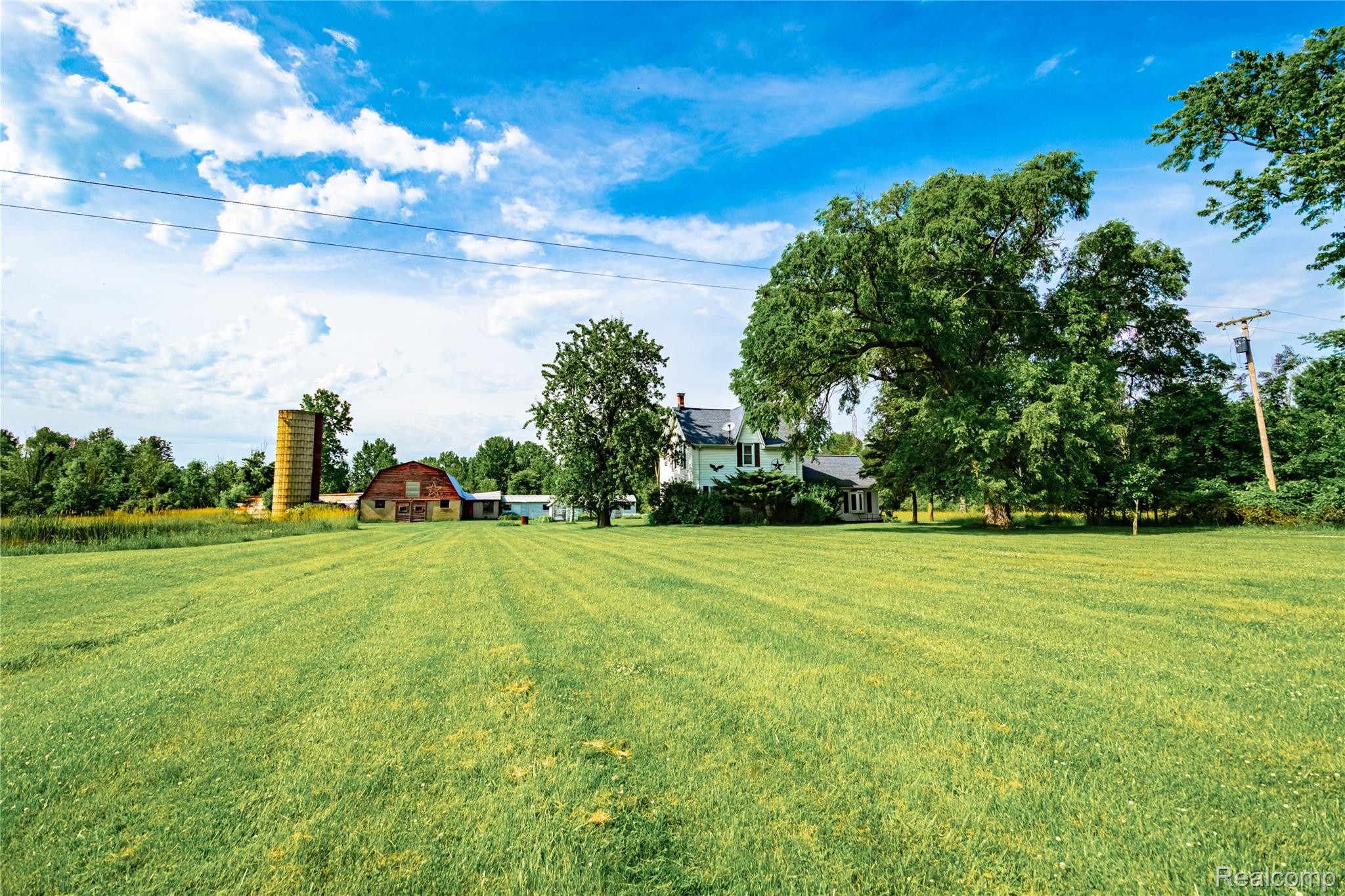 8384 Imlay City Road Avoca, MI 48006 - Photo 10 of 39 Expansive green field extending to a traditional white residence, a red barn, and a silo