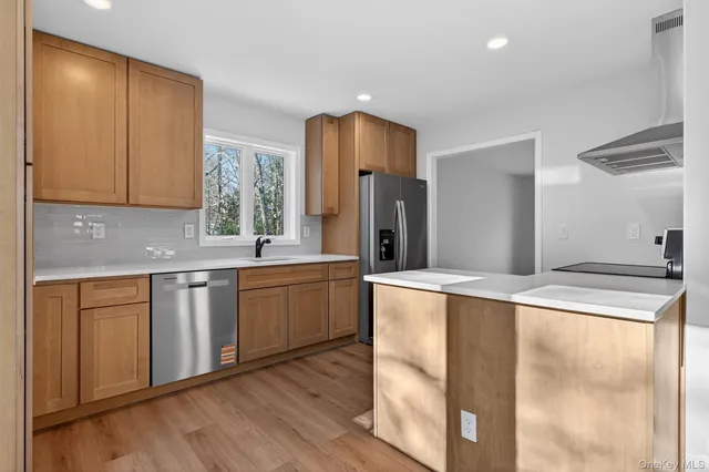 a kitchen with stainless steel appliances granite countertop a refrigerator a sink dishwasher and wooden cabinets with wooden floor