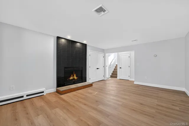 a view of an empty room with wooden floor and a fireplace