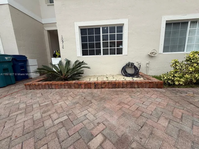 a front view of a house with a yard and potted plants