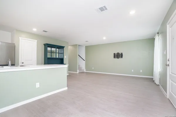 an empty room with windows and way to kitchen