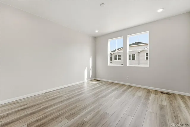 an empty room with wooden floor and windows