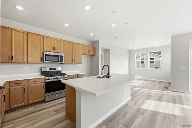 a kitchen with stainless steel appliances granite countertop a stove a sink a refrigerator and white cabinets with wooden floor