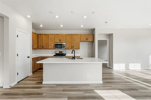 a view of a kitchen with kitchen island a sink wooden floor and a refrigerator