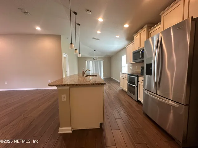 a kitchen with granite countertop a sink and white cabinets with wooden floor