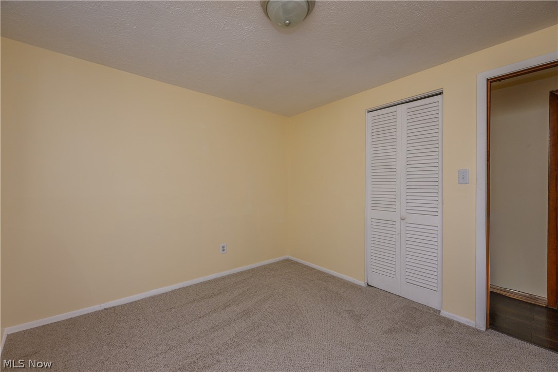 3055 Polly Road Ravenna, OH 44266 - Photo 12 of 25 Unfurnished bedroom featuring carpet flooring, a closet, and a textured ceiling