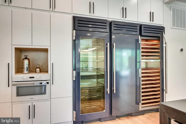 a kitchen with a stove a sink and white cabinets with wooden floor