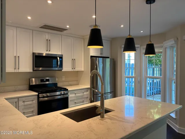 a kitchen with granite countertop a sink a counter top space appliances and cabinets