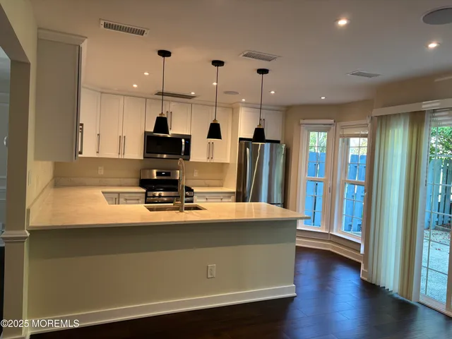 a view of a kitchen with kitchen island a sink stainless steel appliances and cabinets