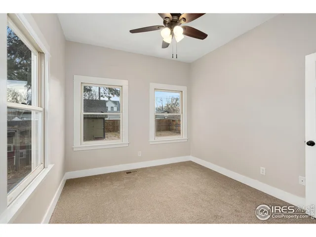 an empty room with windows and ceiling fan