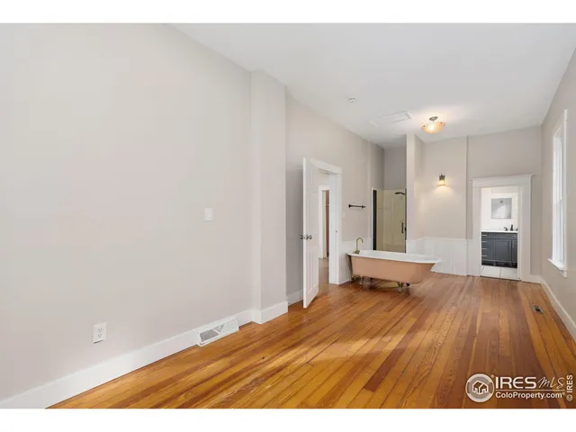 a view of a bedroom with wooden floor and bathroom