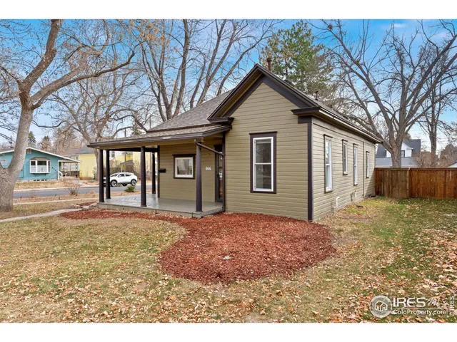 a backyard of a house with large trees and brick wall