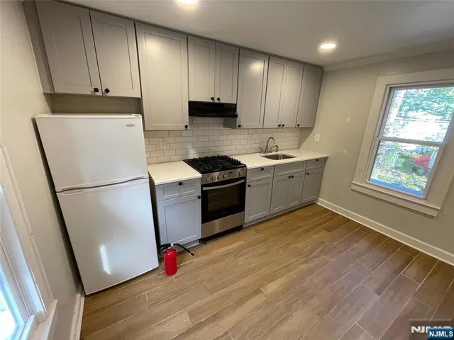 a kitchen with granite countertop stainless steel appliances a refrigerator sink and wooden floor