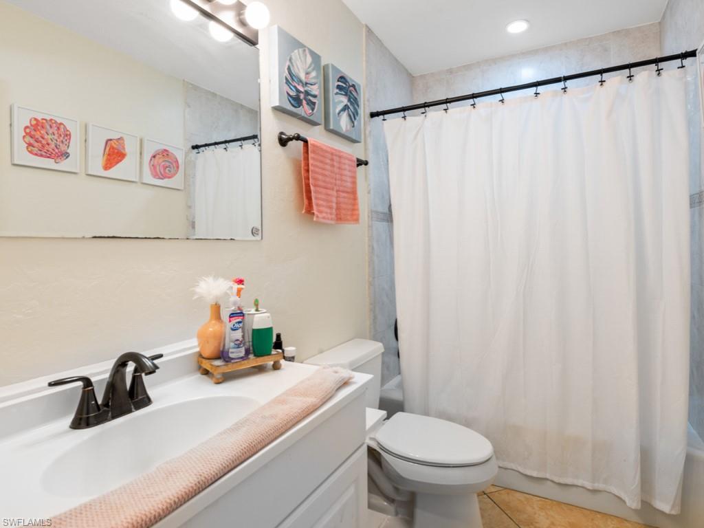 5300 Cypress Lane Naples, FL 34113 - Photo 11 of 14 a bathroom with a sink a toilet and a shower curtain