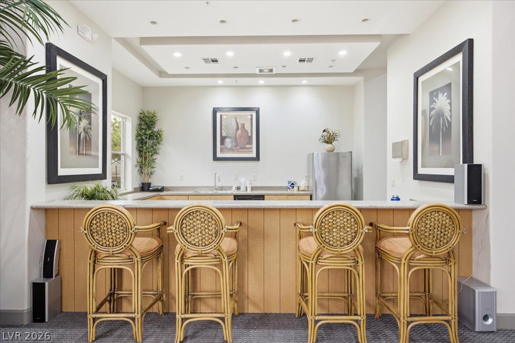 9050 West Warm Springs Road, Unit 1033 Las Vegas, NV 89148 - Photo 25 of 26 A well-lit bar with a tray ceiling and recessed lighting, offering a comfortable gathering space.
