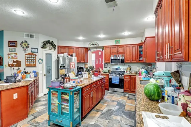 a kitchen with stainless steel appliances kitchen island granite countertop a refrigerator and a stove